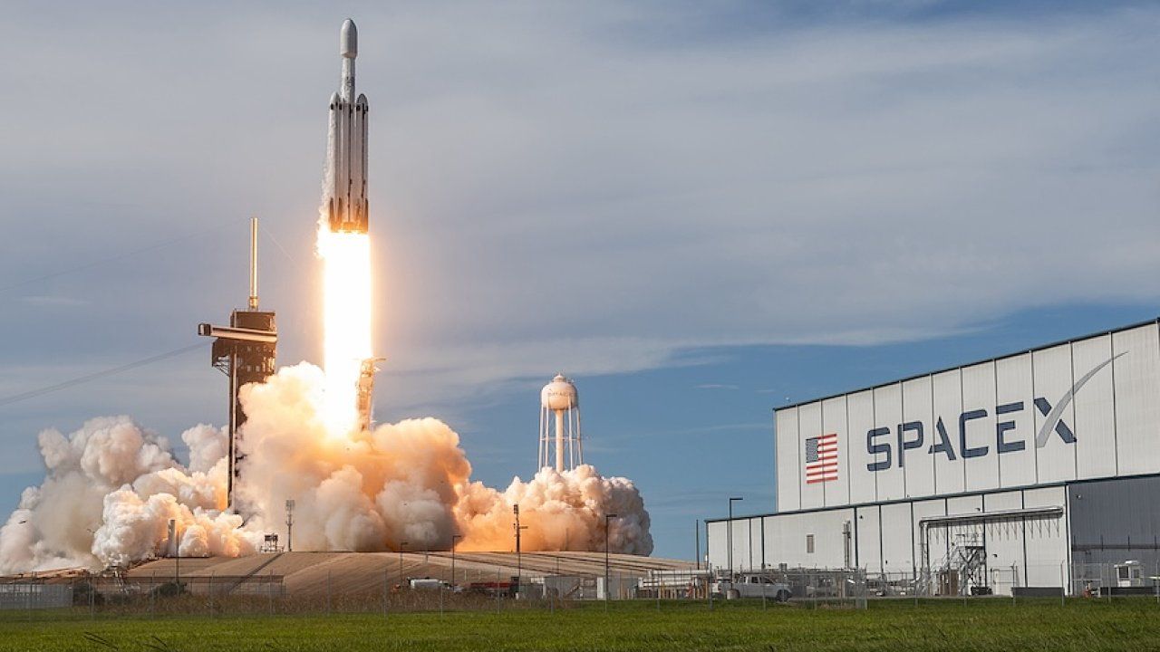 Start rakety Falcon Heavy společnosti SpaceX z rampy u haly s logem SpaceX